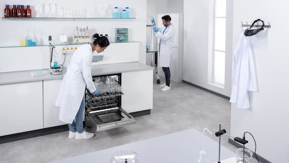 A lab technician opening a laboratory washer containing perfectly dried laboratory glassware.