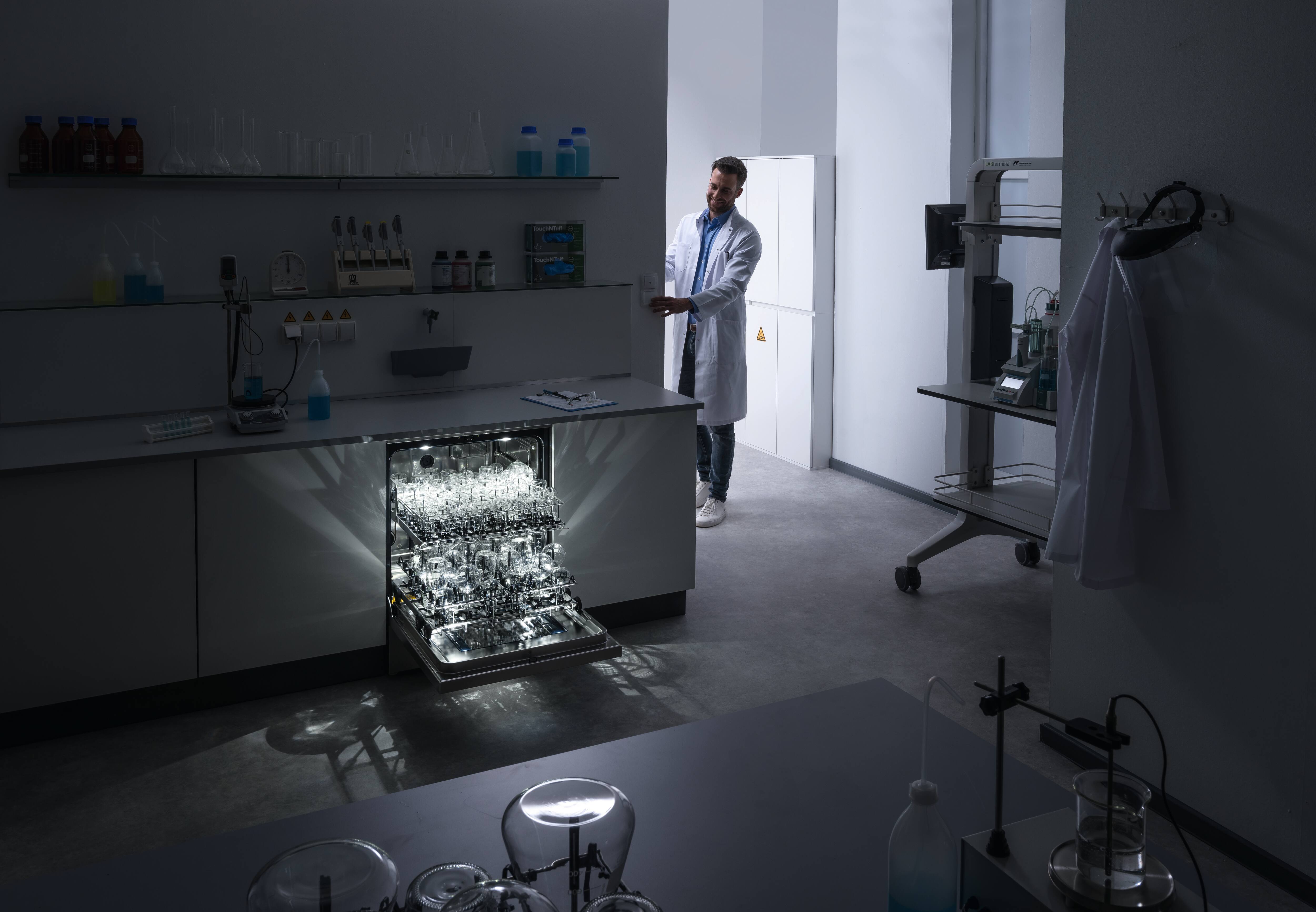 Ein ExpertLine Laborspüler steht in einem dunklen Labor und die Kammerbeleuchtung leuchtet strahlend.