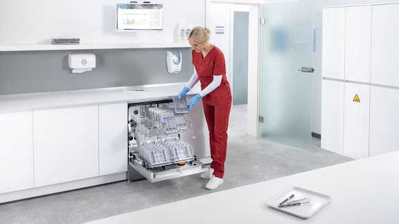 Dental assistant loads ExploreLine dental washer with instruments