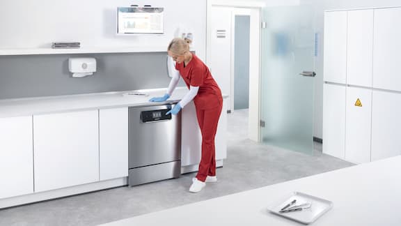 A woman selects programme on ExpertLine medical washer disinfector using the touch display.
