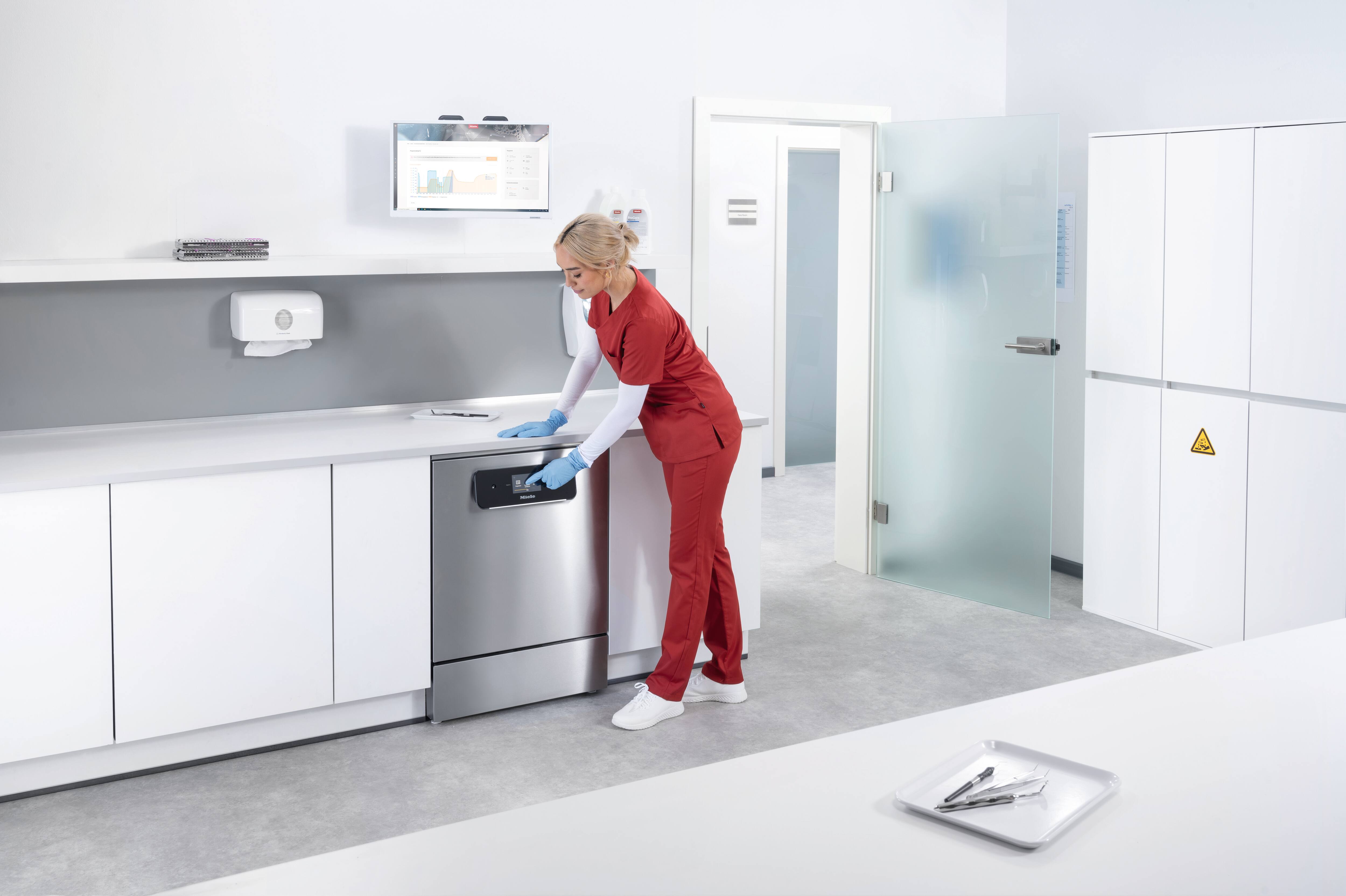 Asystent medyczny obsługuje myjnię-dezynfektor ExpertLine w pomieszczeniu do reprocesowania narzędzi medycznych.