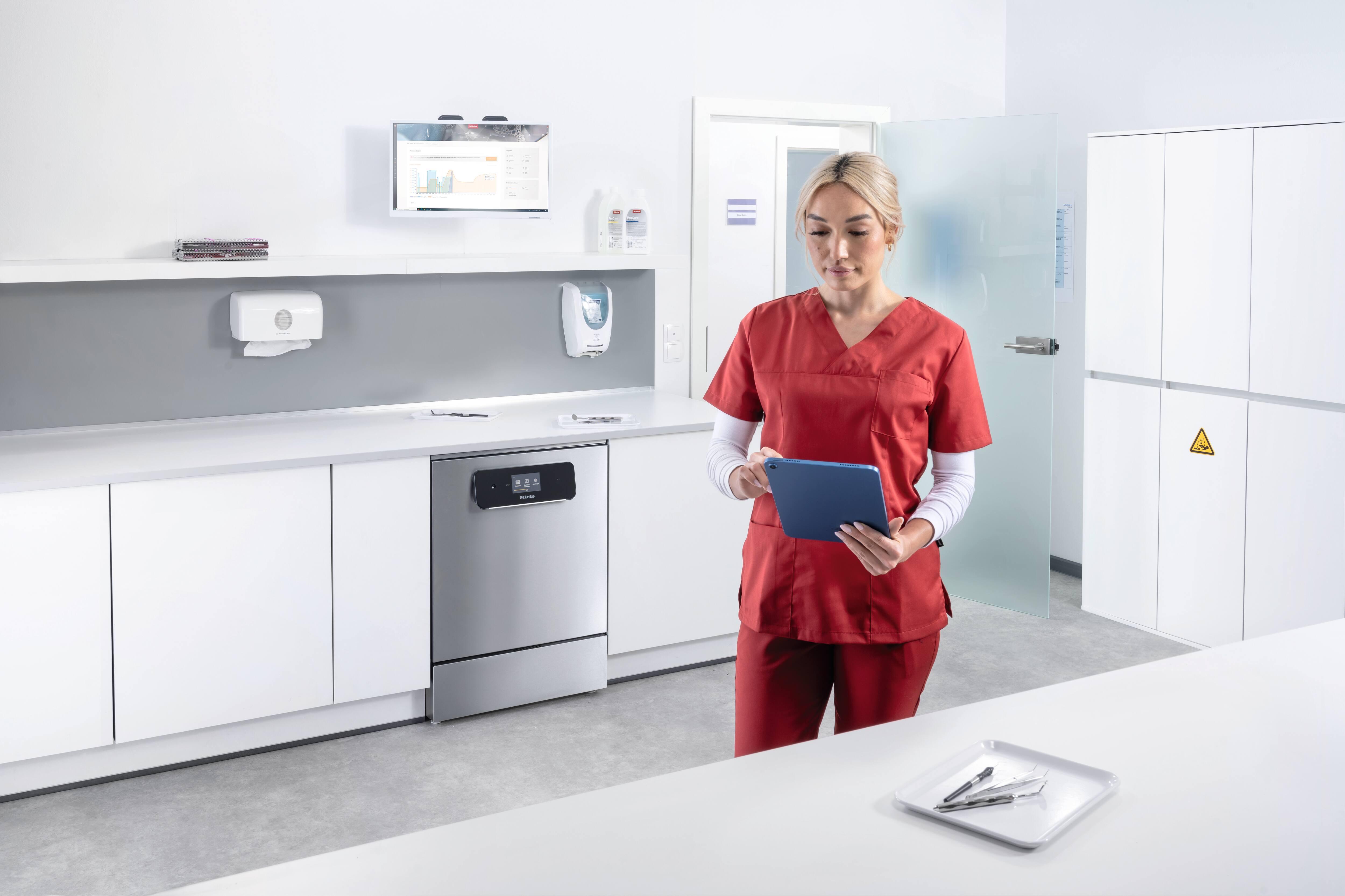 A dental assistant looks at a tablet in an instrument reprocessing room