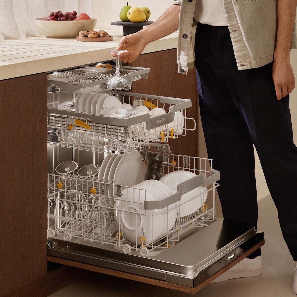 person placing a glass in a dishwasher