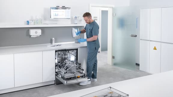 Medical assistant walks inside medical reprocessing room with ExpertLine washer disinfector