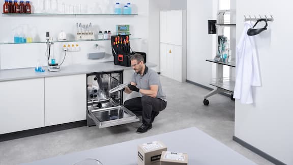 A service technician checking the spray arm of an open ExpertLine laboratory washer.