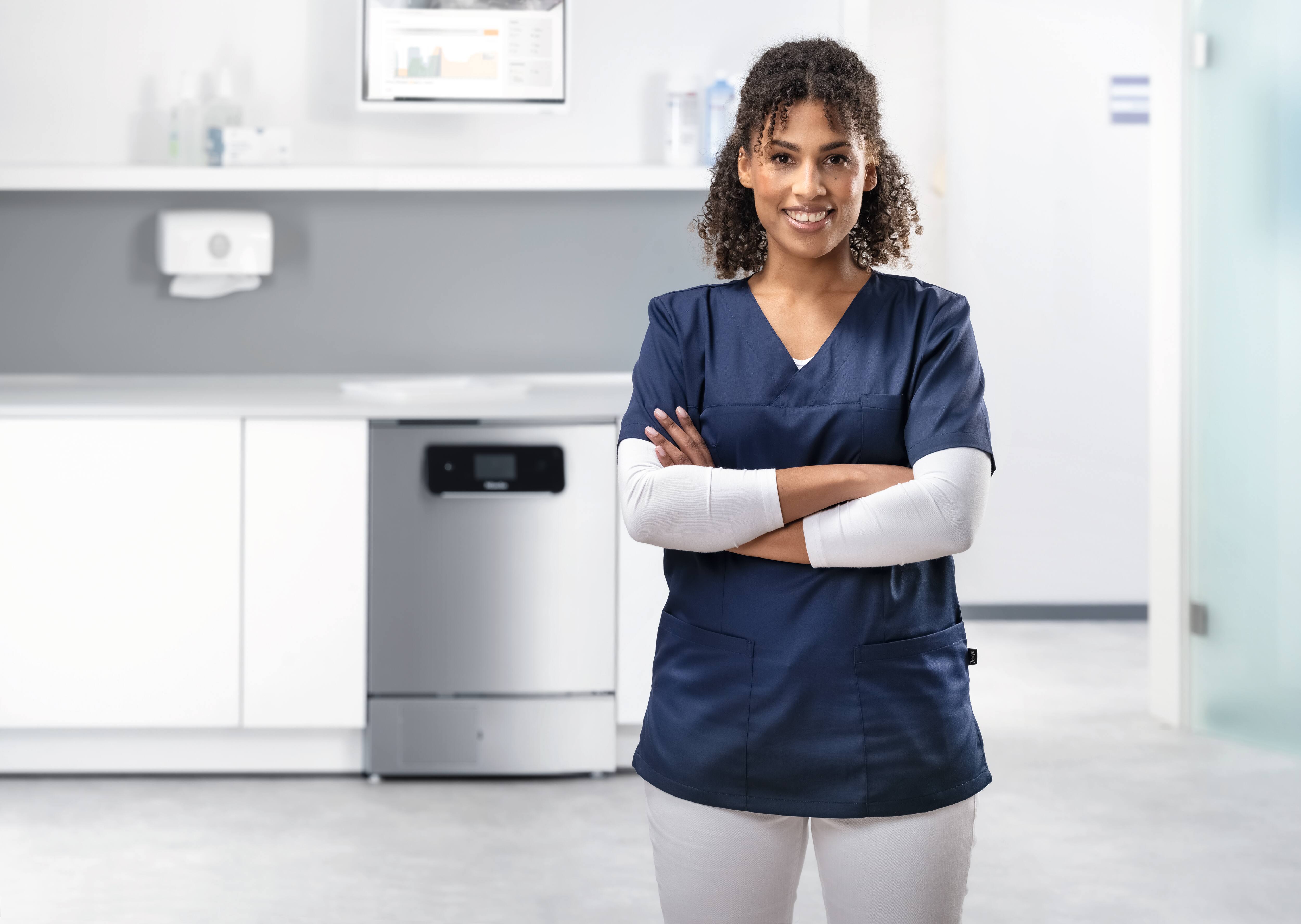 A doctor smiles at camera from reprocessing room with ExpertLine wsher-disinfector