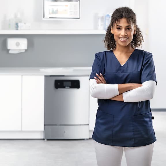A doctor smiles at camera from reprocessing room with ExpertLine wsher-disinfector