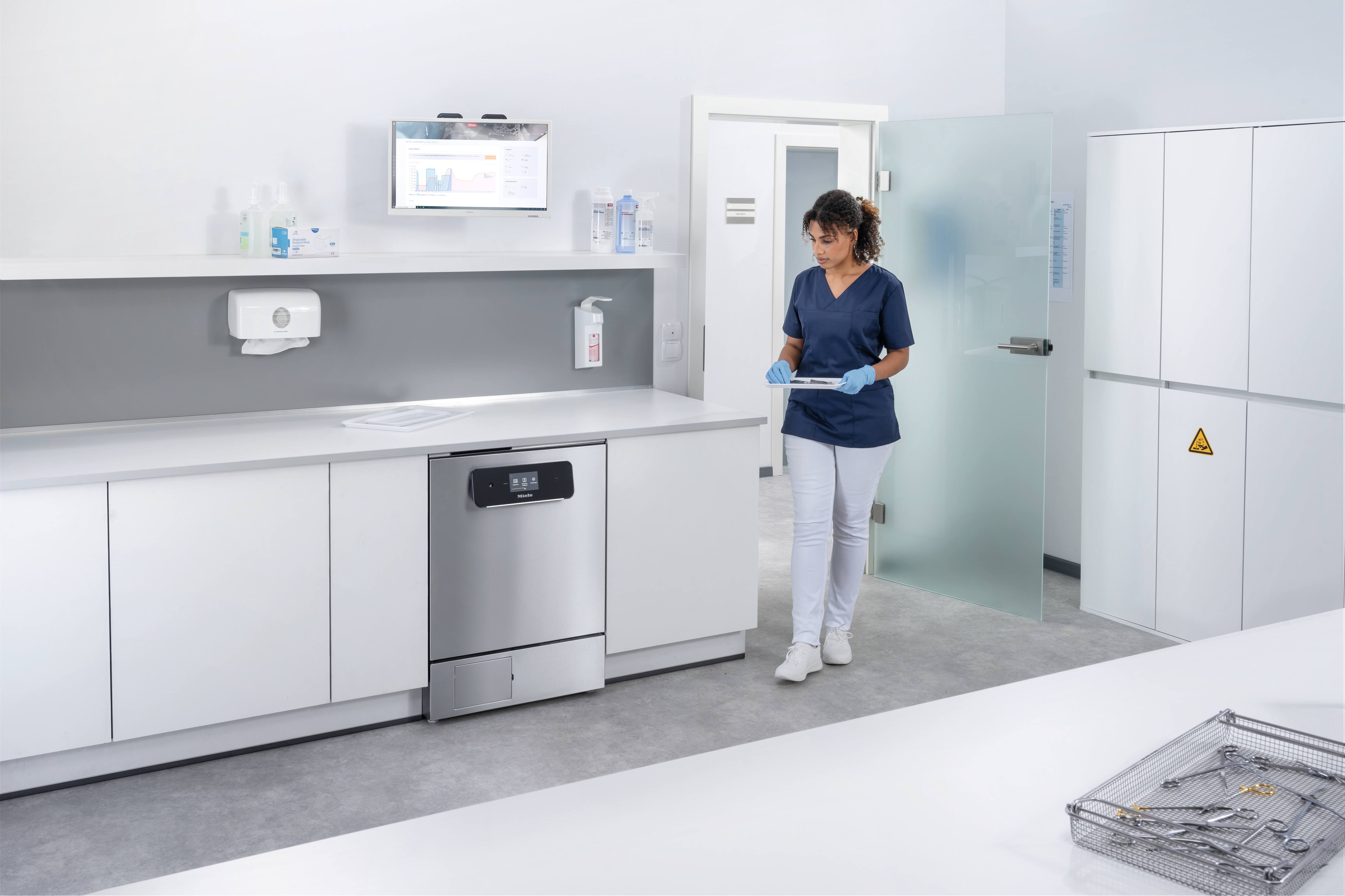 Medical assistant enters reprocessing room with ExpertLine washer disinfector