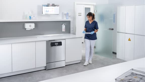 Medical assistant enters reprocessing room with ExpertLine washer disinfector