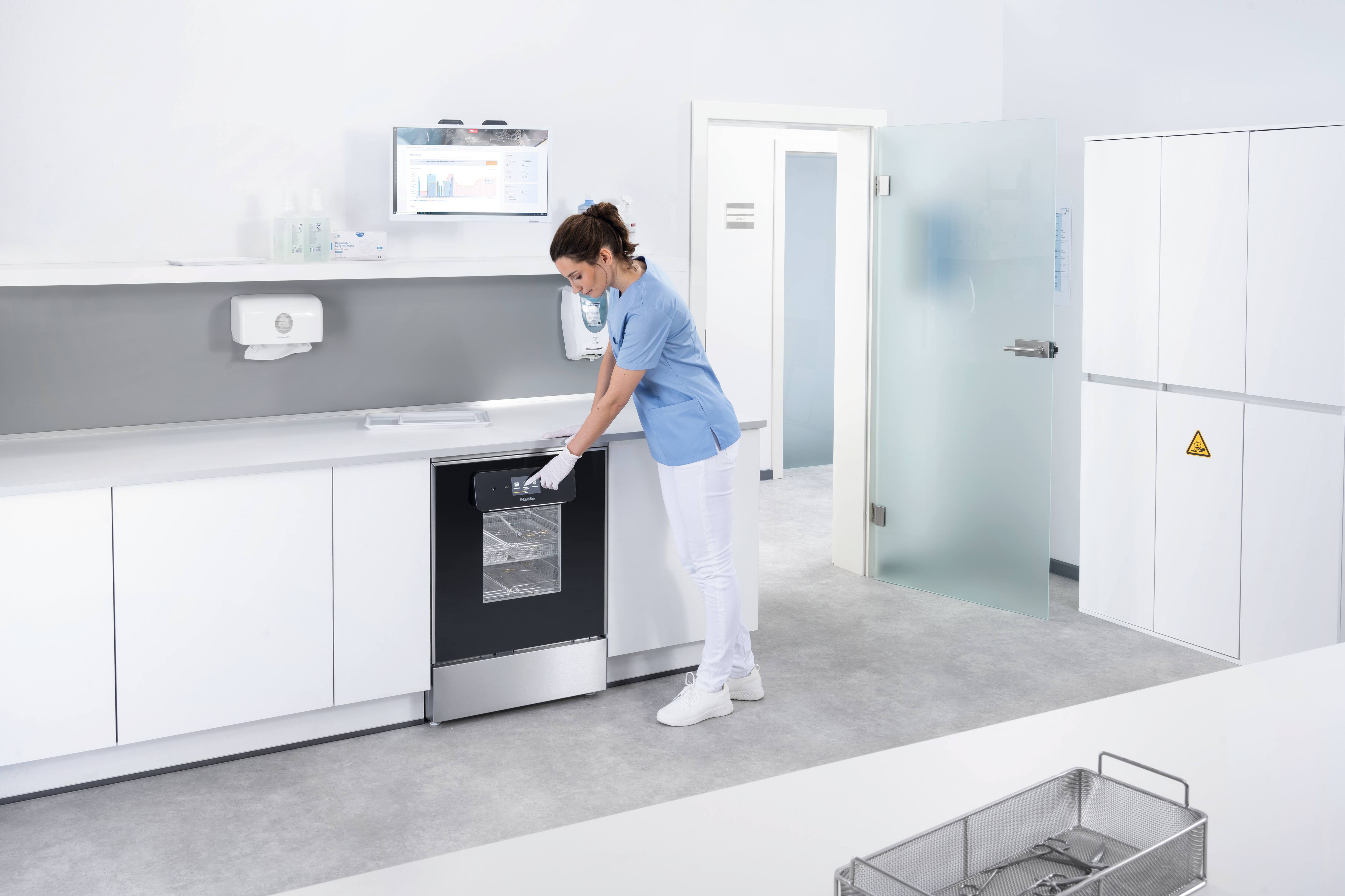Zdravotnický asistent vybírá program na mycím a dezinfekčním automatu řady ExpertLine v lékařské místnosti pro přípravu instrumentů