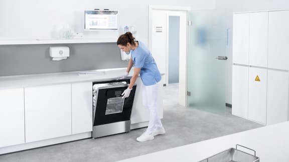 Een tandartsassistente werkt in de ruimte voor instrumentenbehandeling met de ExpertLine thermodesinfector