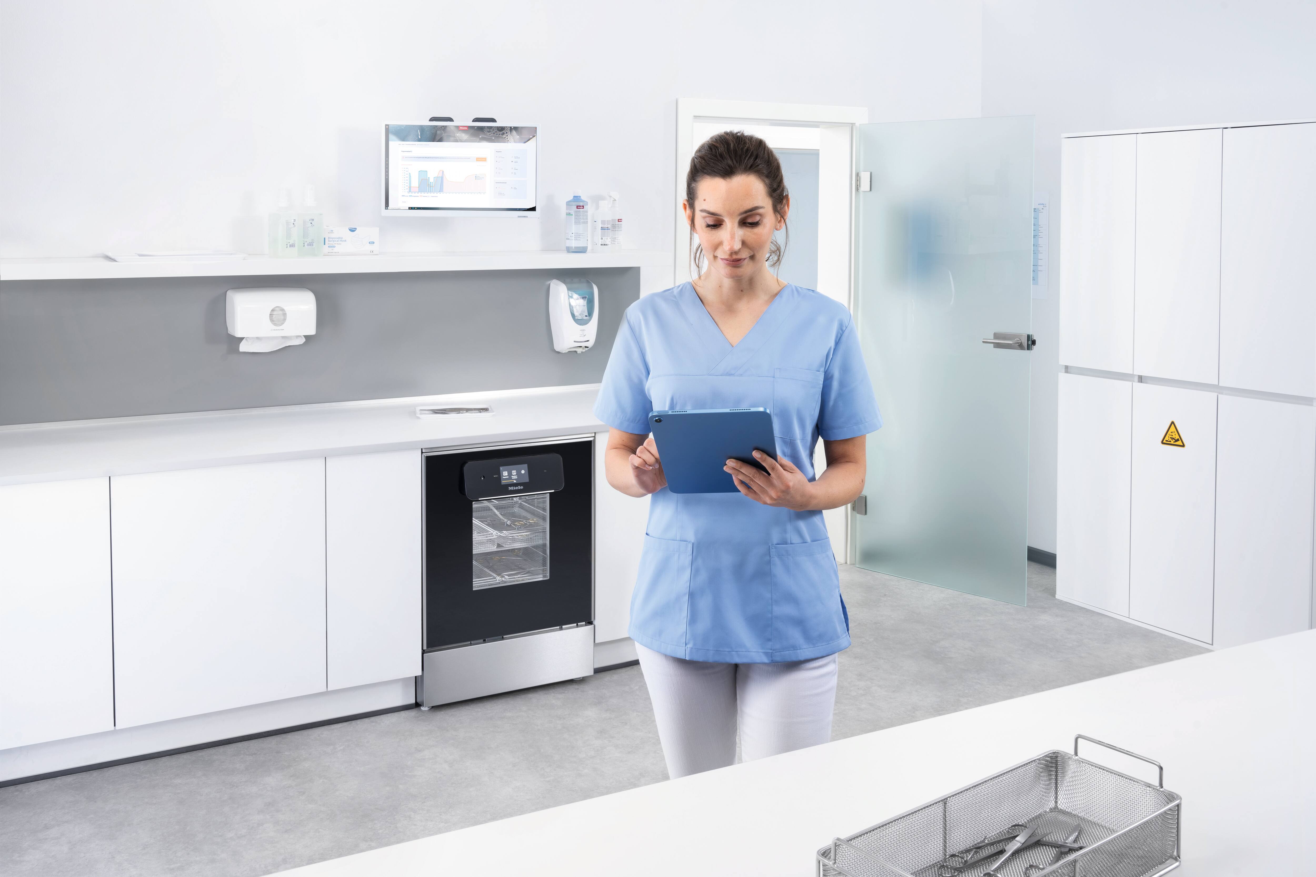 Eine Frau hält ein Tablet im Raum für die Instrumentenaufbereitung