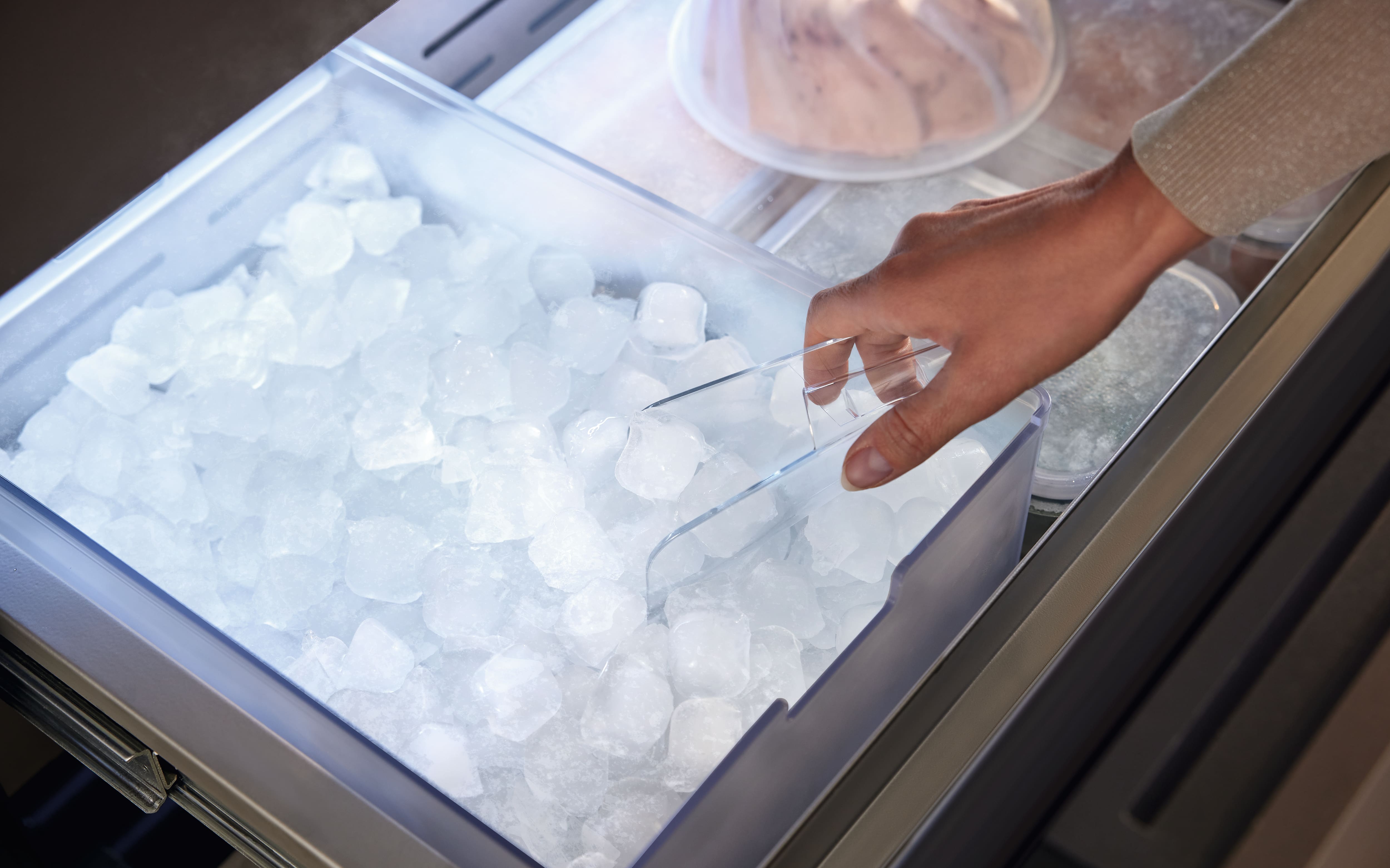Detailed view of the new MasterCool refrigerator IceMaker drawer interior, showcasing a person taking out some ice cubes. Detailed view of the new MasterCool refrigerator IceMaker drawer interior, showcasing a person taking out some ice cubes.