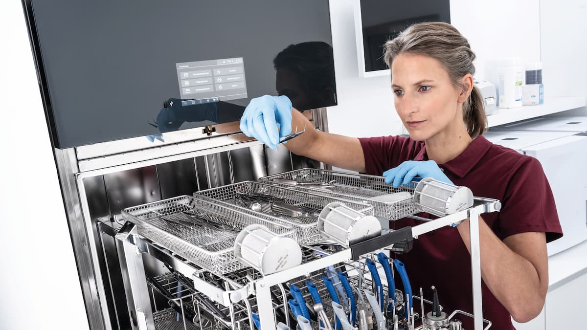 Dental assistant inspects dental instruments by Miele Professional SlimLine thermal disinfector