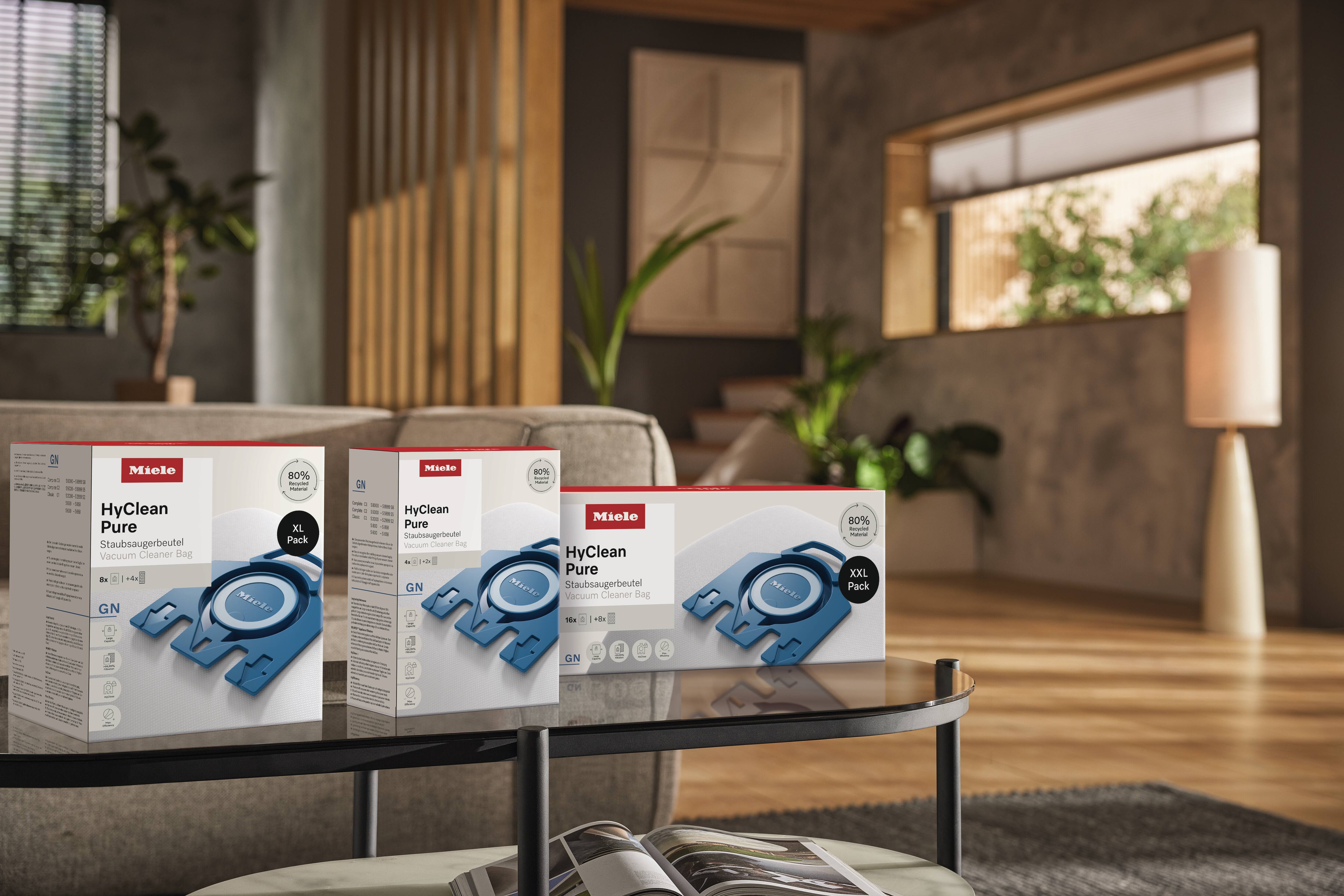 Trzy pudełka z workami do odkurzaczy Miele na stoliku kawowym w nowoczesnym wnętrzu