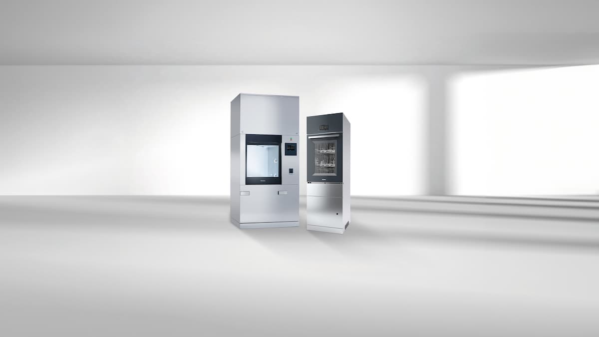Zwei Großraumlaborspüler, die für die industrielle Teilereinigung verwendet werden können stehen nebeneinander auf einem grauen Fond.