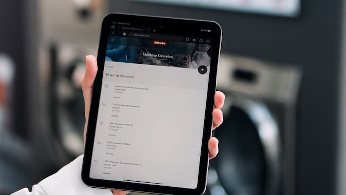 Jemand hält ein Tablet, das eine Liste mit vernetzten Maschinen anzeigt.
