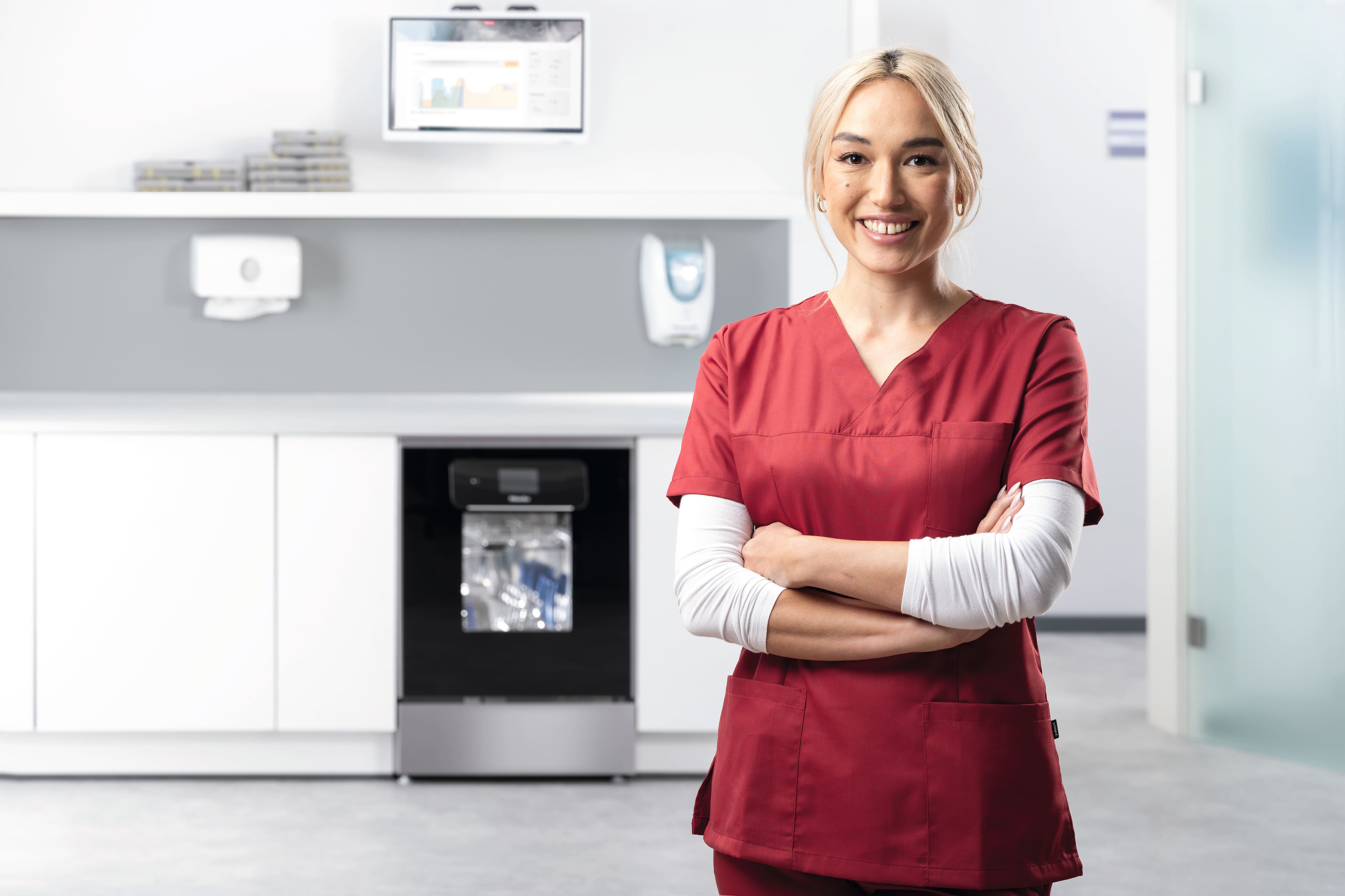 Ένας βοηθός οδοντιατρείου χαμογελά στην αίθουσα καθαρισμού-απολύμανσης με μια συσκευή ExpertLine