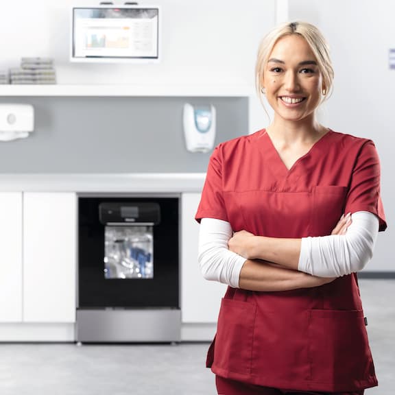 Asystentka stomatologiczna uśmiecha się w pomieszczeniu do reprocesowania z urządzeniem ExpertLine