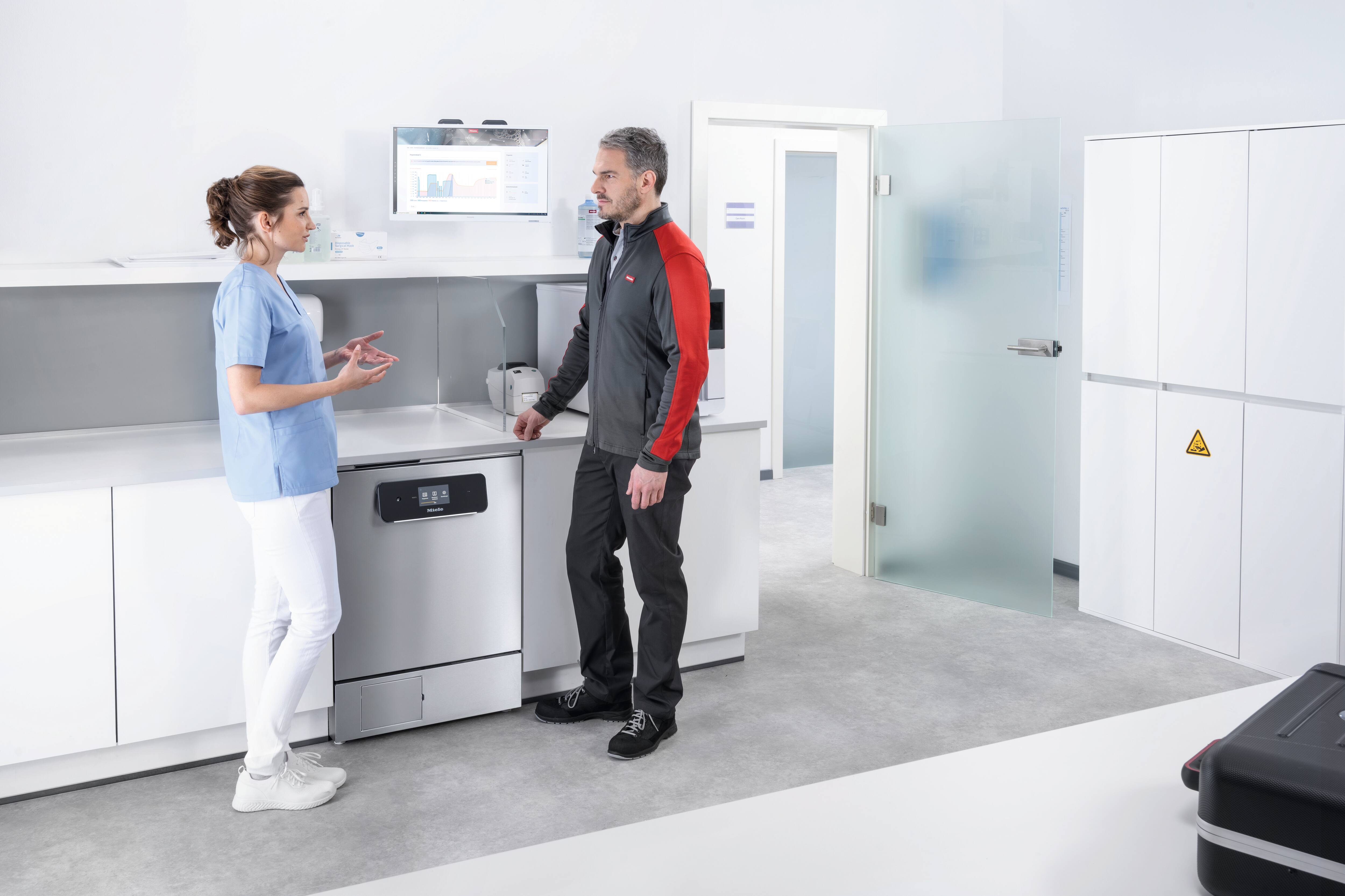 Servis teknisyeni doktor asistanı ile birlikte küçük sterilizatörü kontrol ediyor.