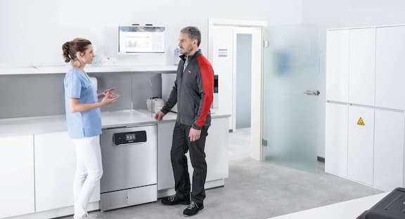 Servis teknisyeni doktor asistanı ile birlikte küçük sterilizatörü kontrol ediyor.