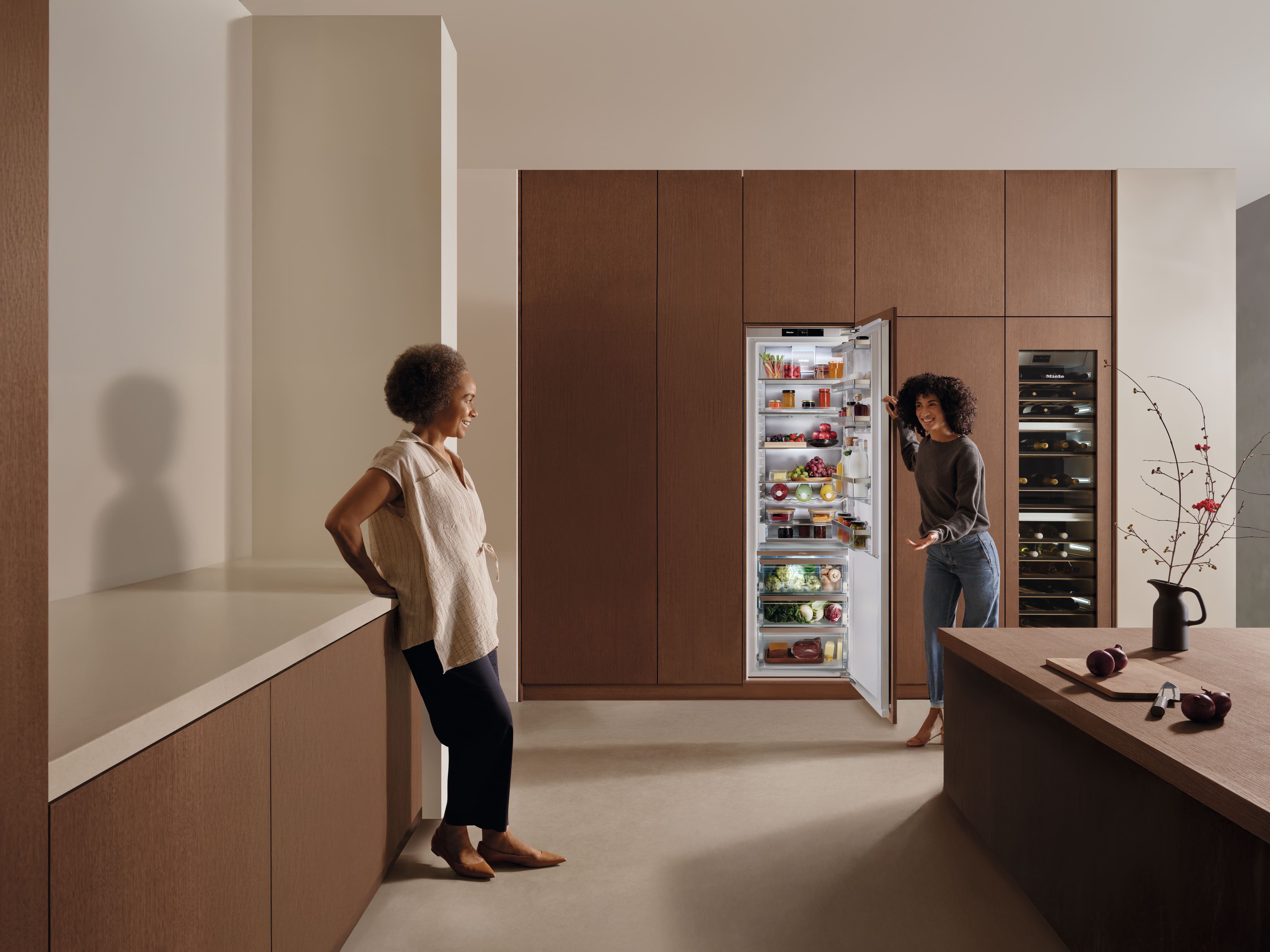 Ragazza in cucina con accanto un Frigo-congelatore Miele