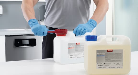 Le technicien de service ouvre le bidon de ProCare Dent avec la clé du bidon.