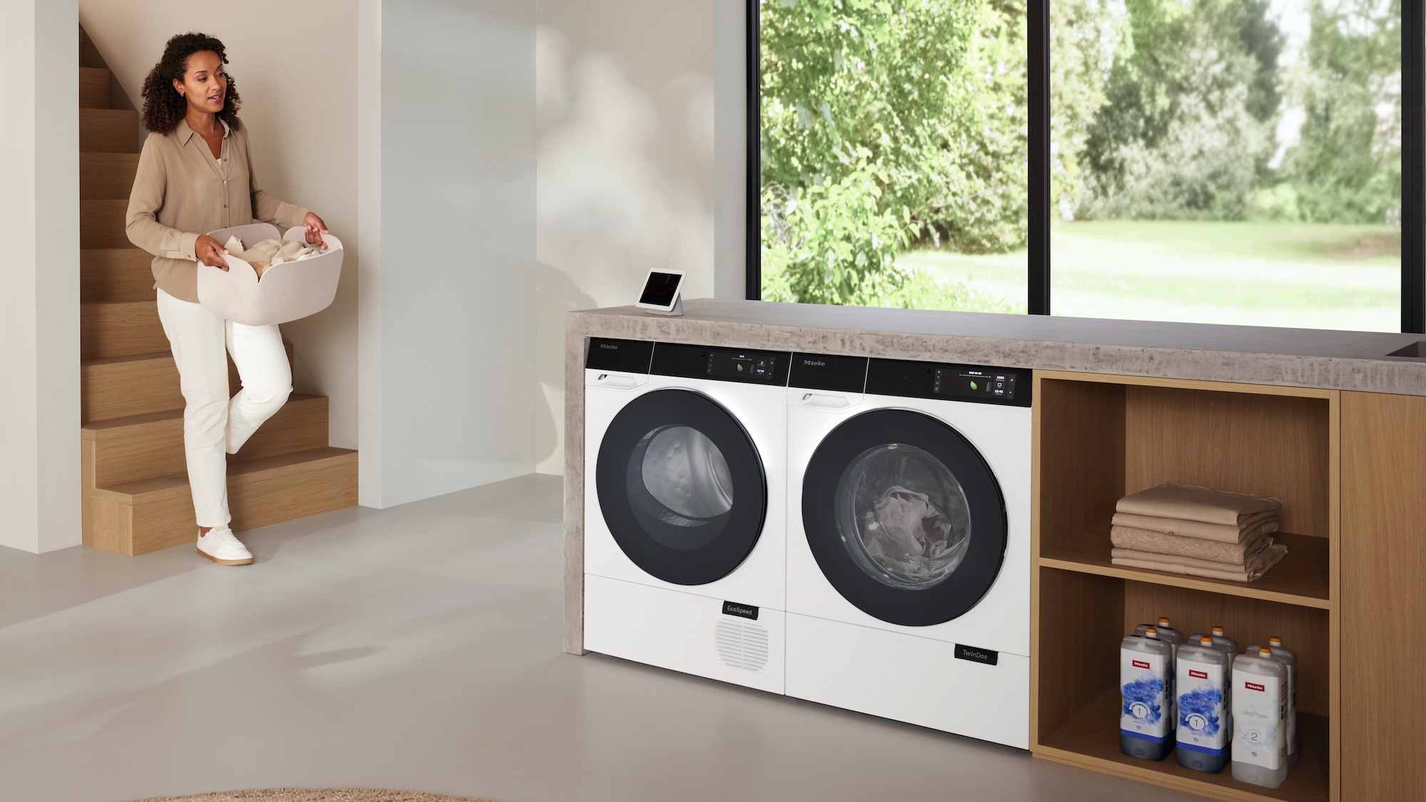 Moteris, nešanti skalbinius žemyn prie skalbyklės ir džiovyklės