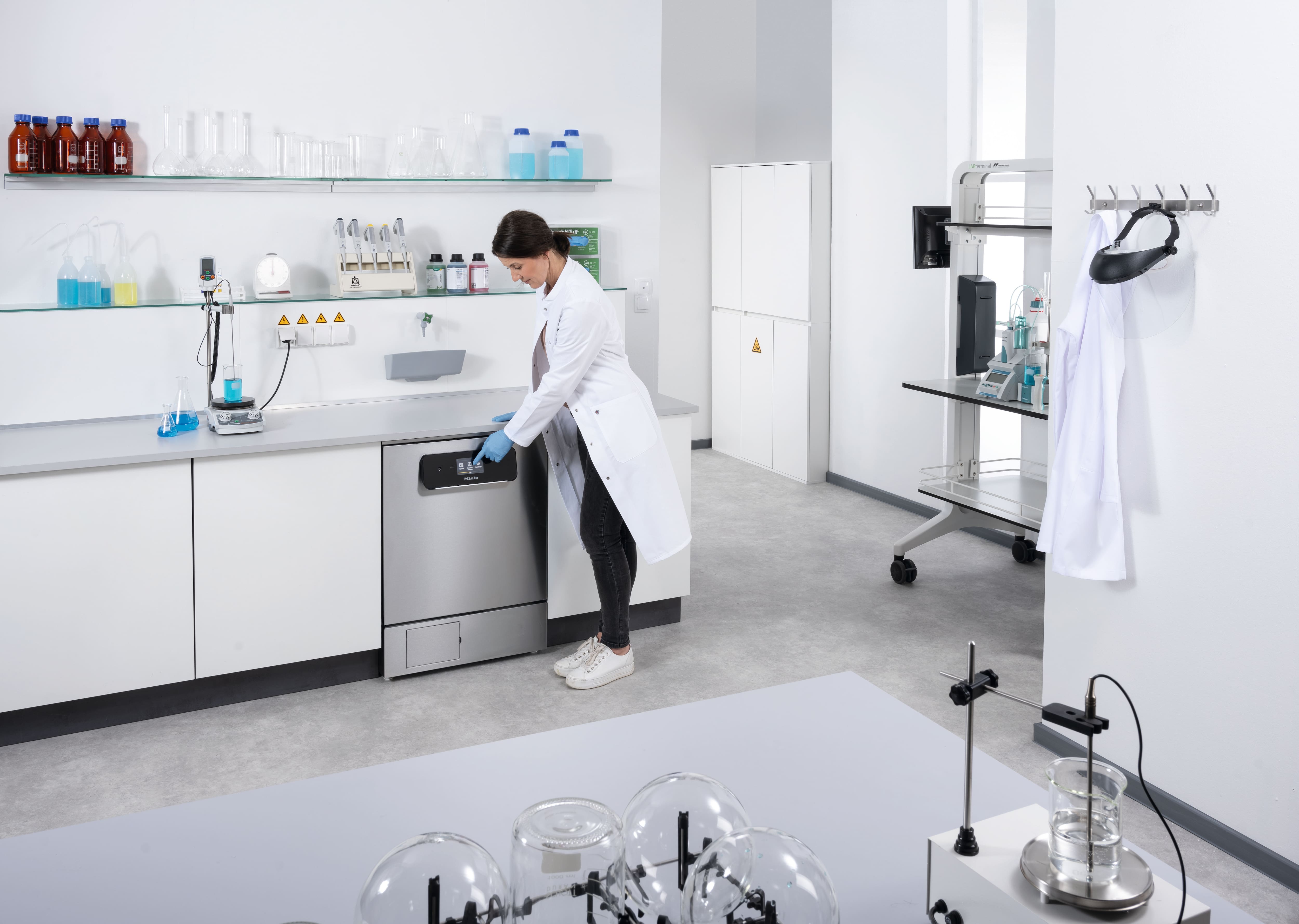 Labormitarbeiterin bedient einen Untertisch-Laborspüler PLW 8693 in einem modernen, hellen Labor.