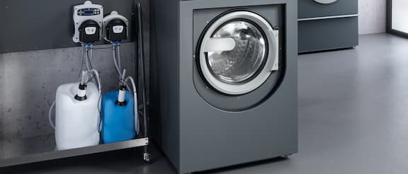 A PWM 514 Benchmark Performance washing machine is connected to an automatic dispensing system.