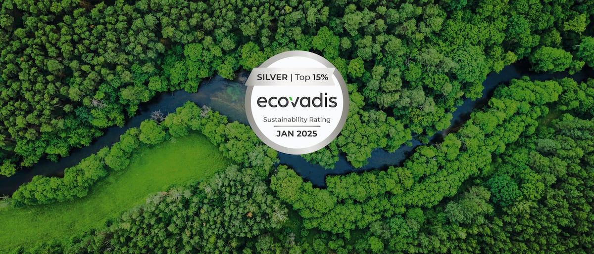 Aerial view of a dense forest with a river winding through the greenery. In the center of the image is a round EcoVadis logo with the text 'SILVER | Top 15% ecovadis Sustainability Rating JAN 2025'.