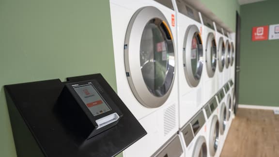 The modern appWash Pay payment system can be seen in the foreground. The image also shows several Little Giants washing machines and tumble dryers set up as a practical washer-dryer stacking kit.