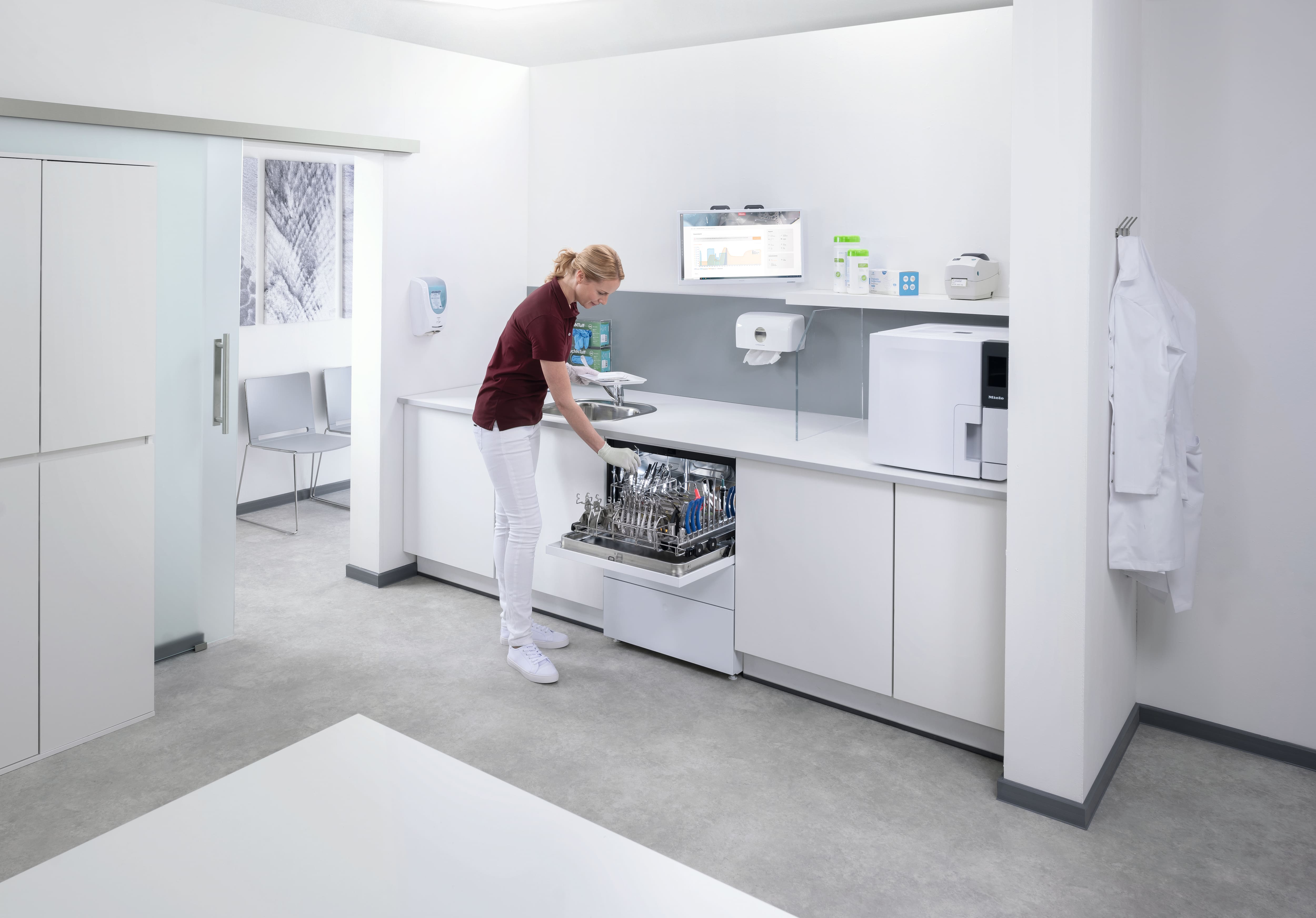 Eine Zahnarzthelferin entlädt den Thermaldisinfector CompactLine im Aufbereitungsraum.