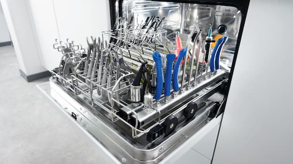 Une main ouvre la porte d’un laveur-désinfecteur CompactLine chargé d’instruments dentaires propres après le cycle de lavage.