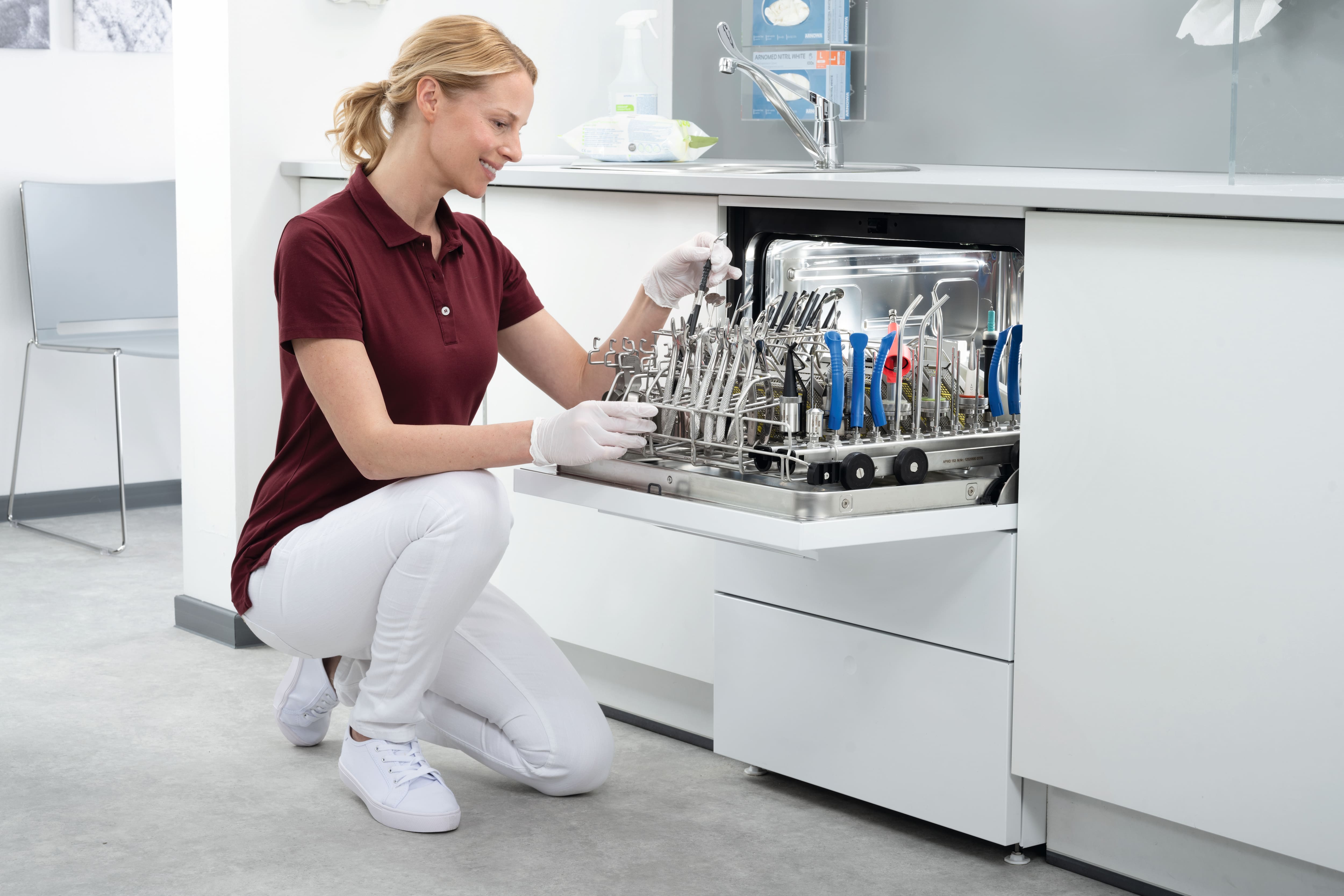 Eine Assistentin schaut in den mit zahnärztlichen Instrumenten beladenen CompactLine-Thermodesinfektor.