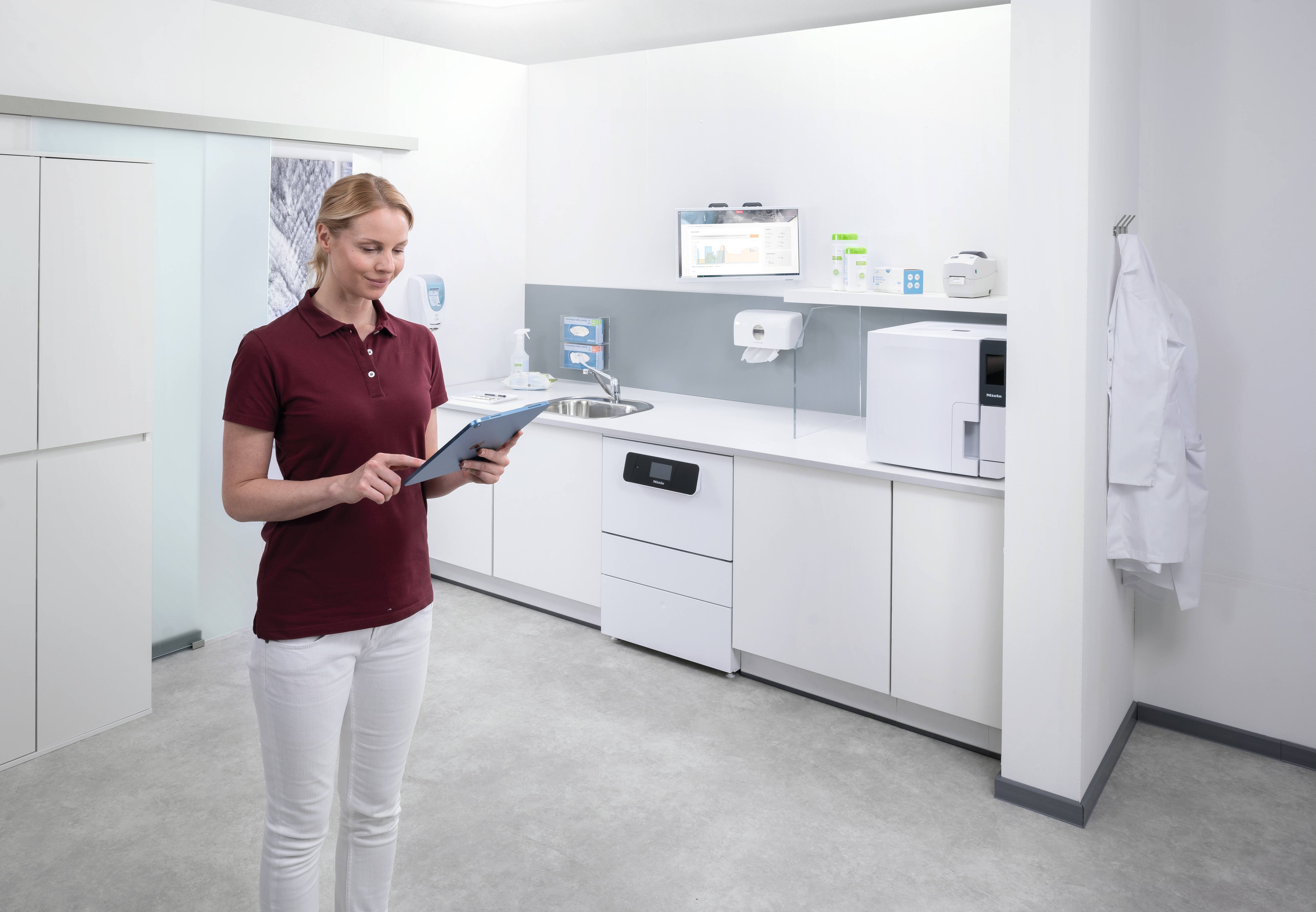 Eine Zahnarzthelferin schaut auf ein Tablet im Aufbereitungsraum.