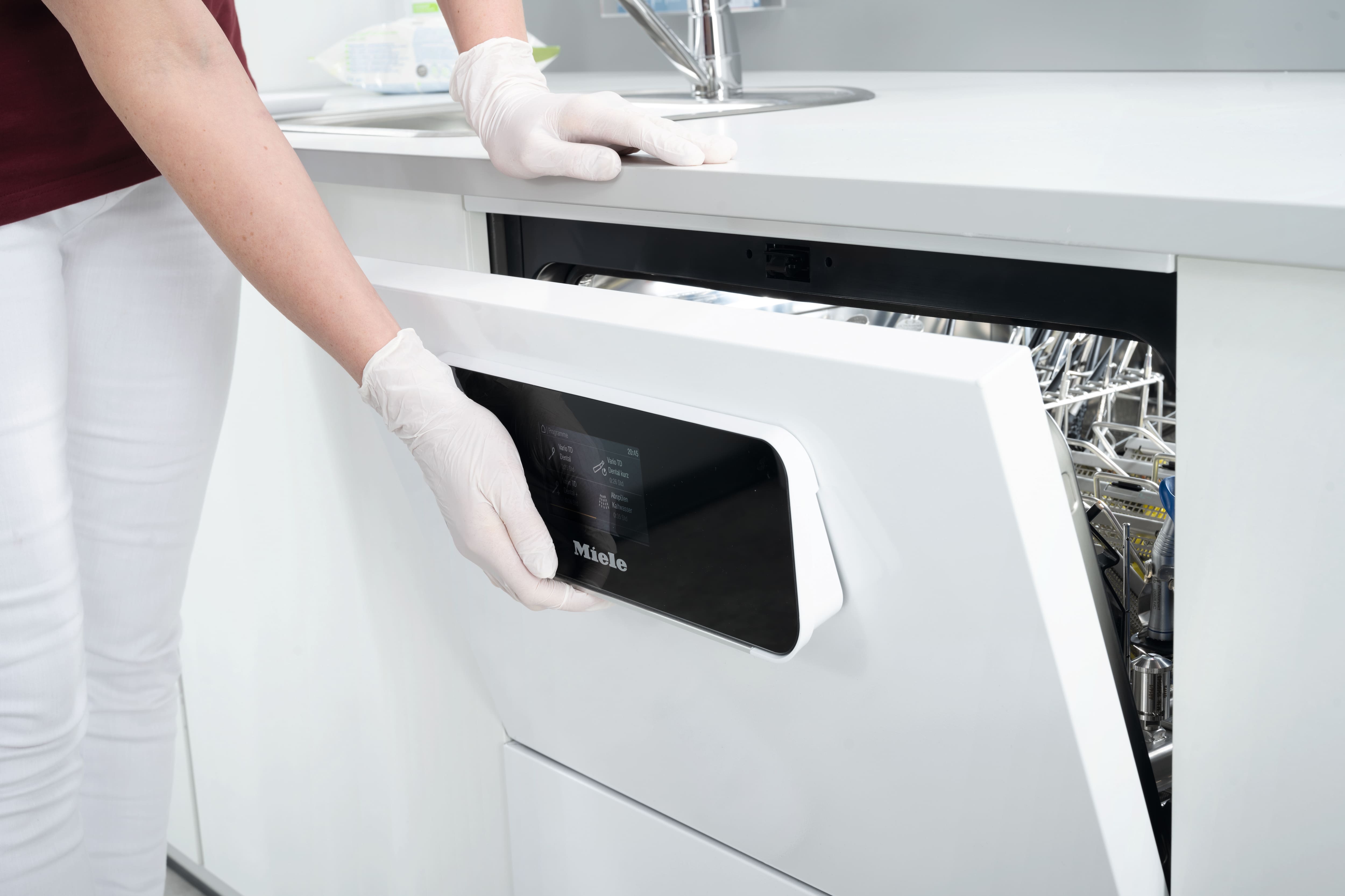 Eine Hand öffnet die Tür eines CompactLine-Thermodesinfektionsgeräts.