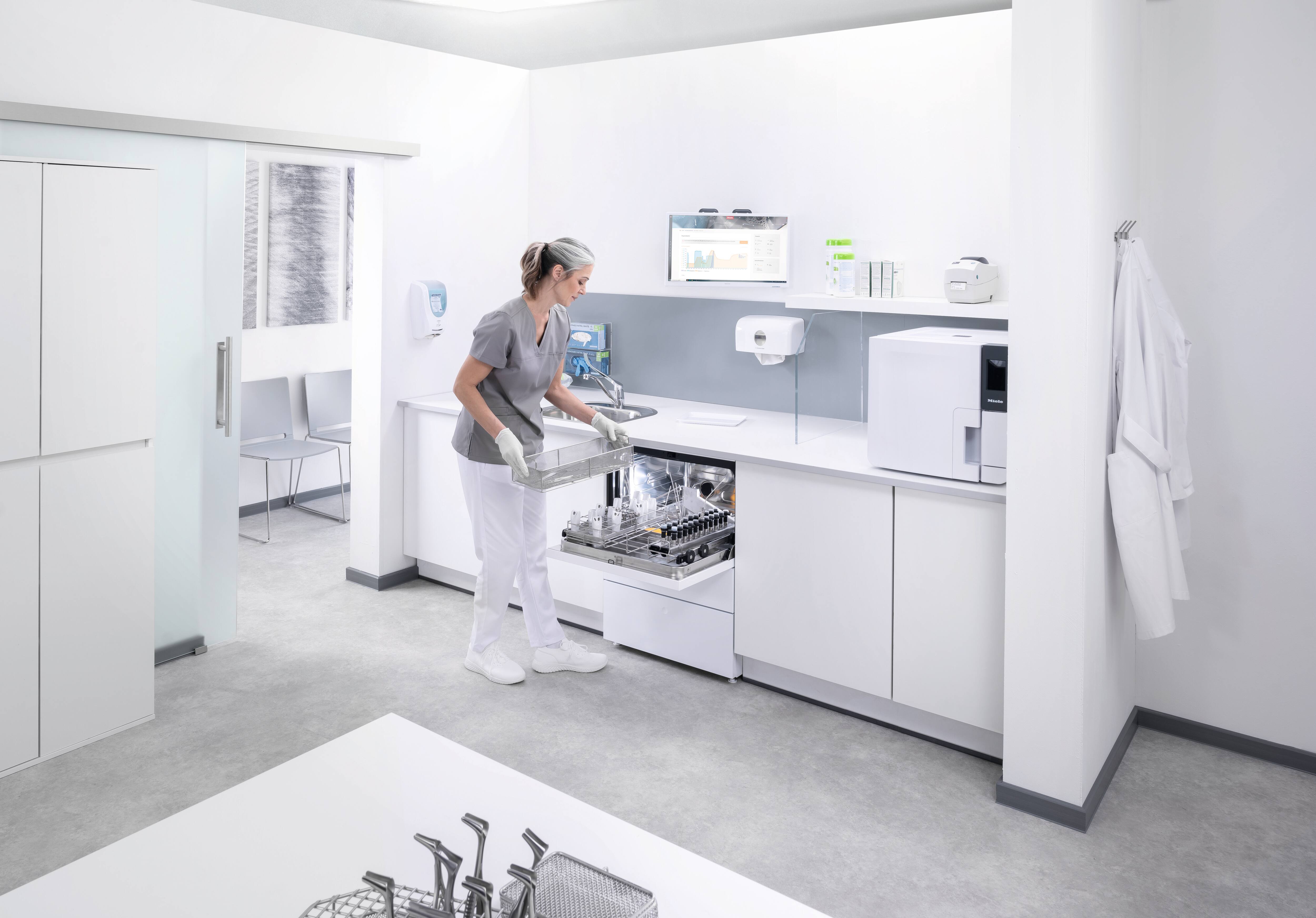 Eine medizinische Assistentin entlädt ein Reinigungs- und Desinfektionsgerät der Serie CompactLine im Instrumentenaufbereitungsraum.