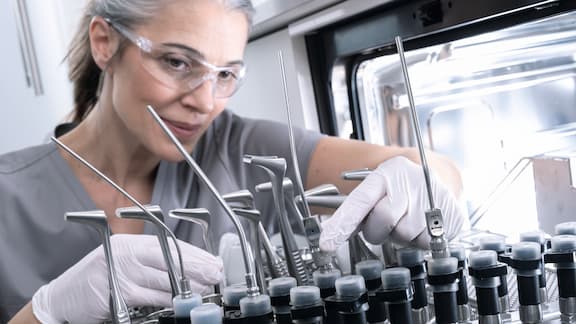 Uma assistente médica descarrega instrumentos ORL da máquina de lavar e desinfetar CompactLine