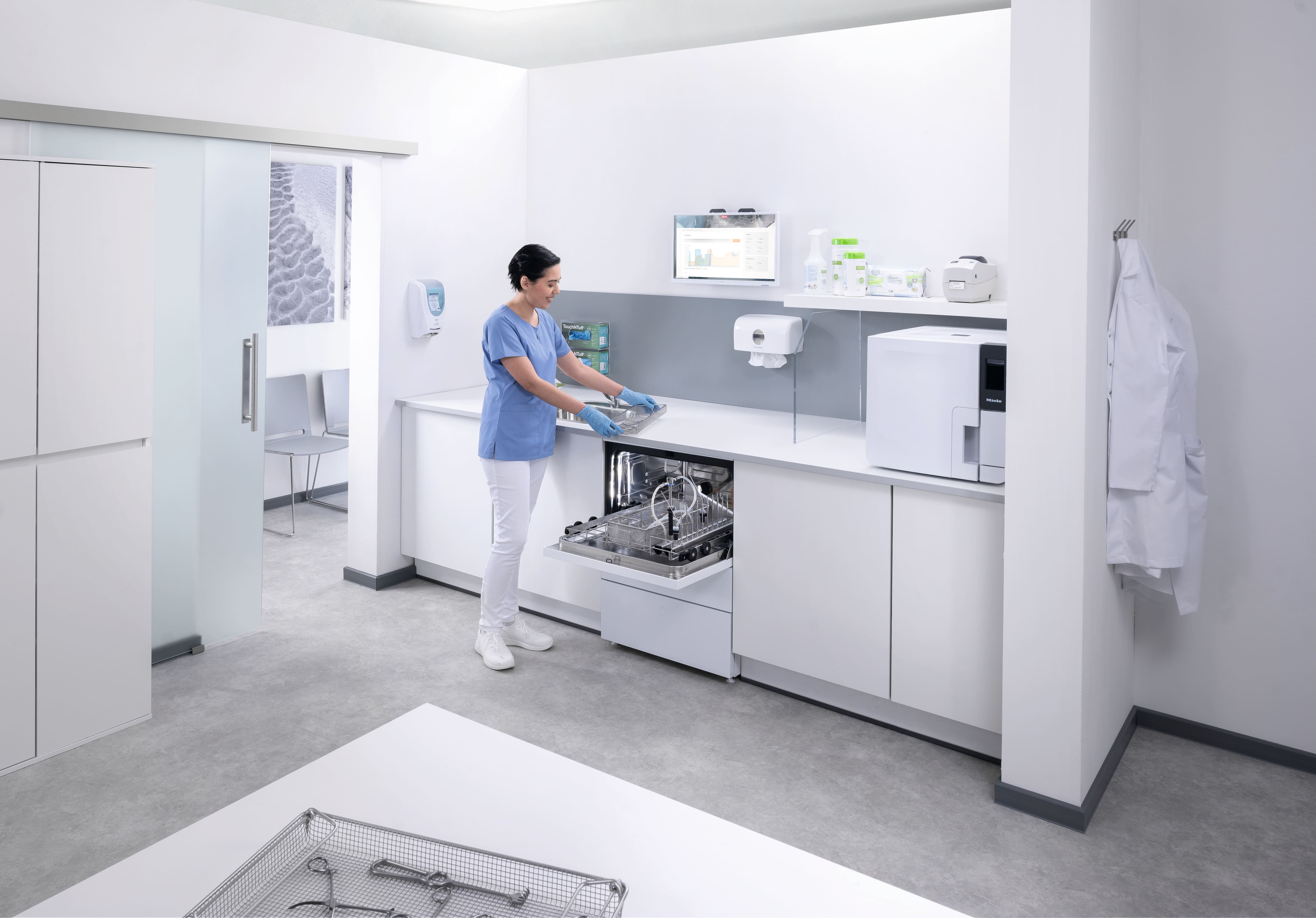 Medizinische Fachangestellte im Instrumentenaufbereitungsraum entlädt einen CompactLine-Reinigungs- und Desinfektionsgerät.