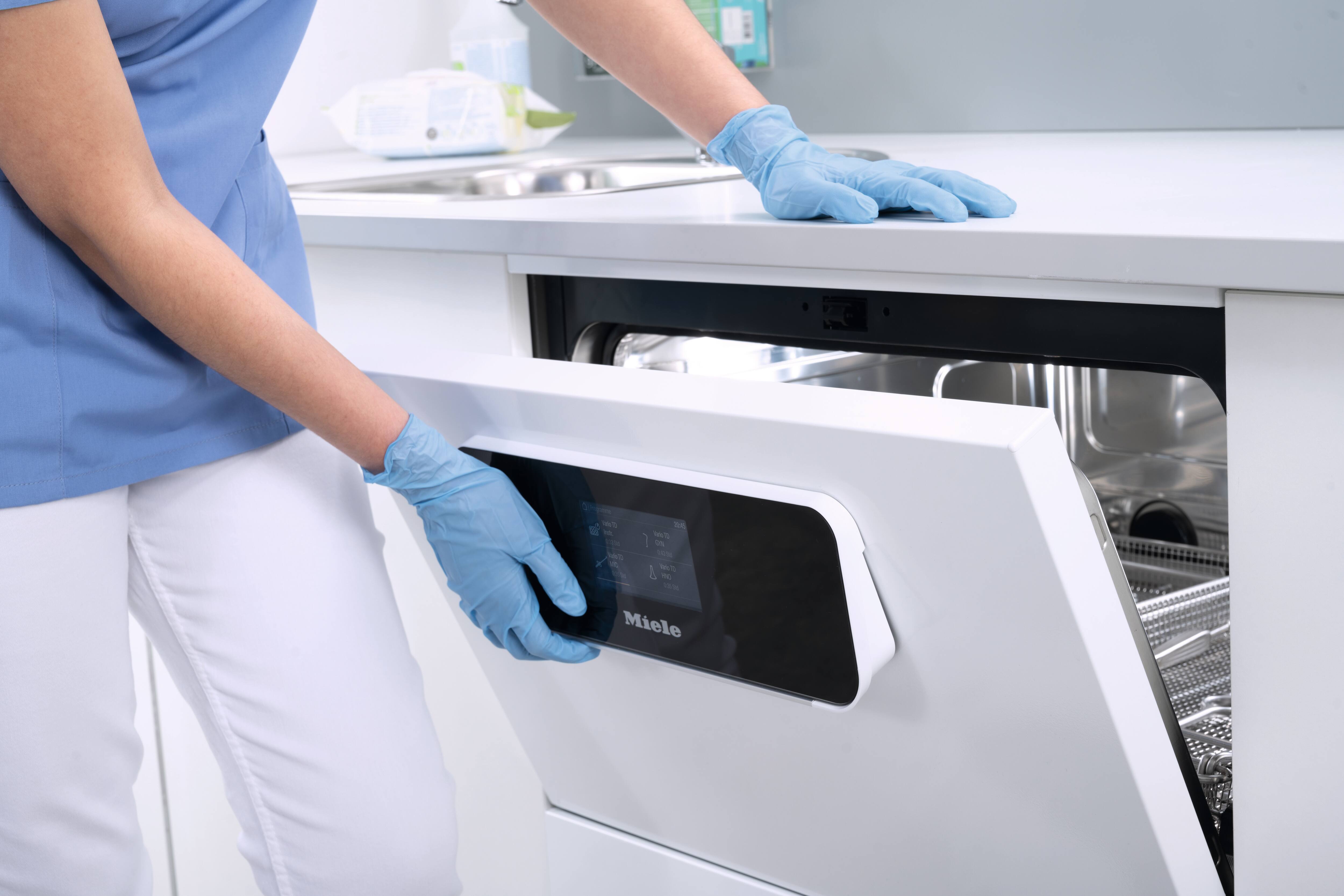 Eine Hand mit Handschuh öffnet die Tür eines CompactLine-Reinigungs- und Desinfektionsgeräts.