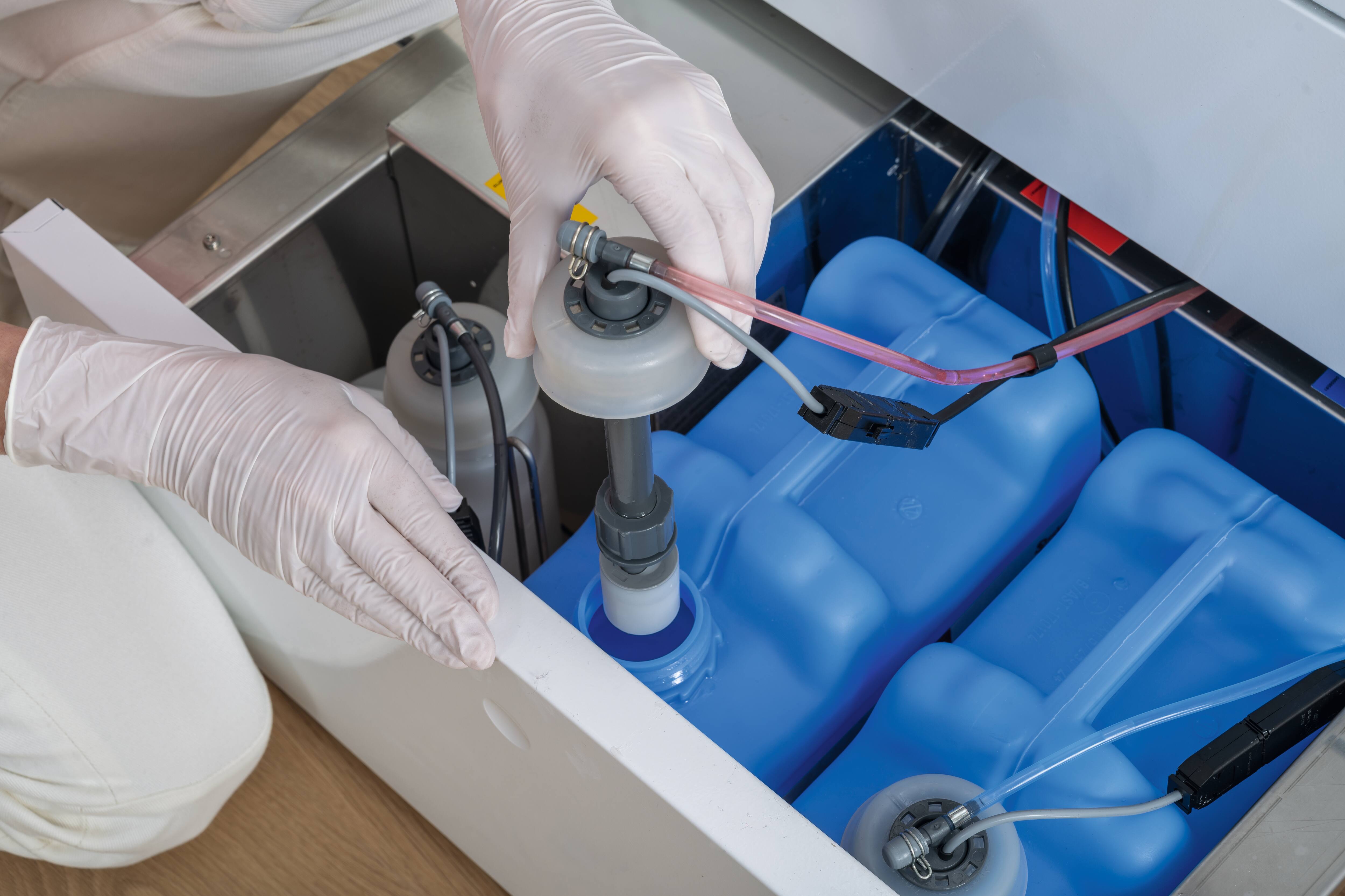 Eine Hand zieht eine Sauglanze aus einem Behälter im Inneren der Schubladen des CompactLine-Reinigungs- und Desinfektionsgeräts.