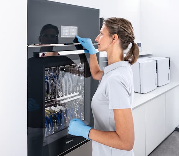 Een vrouw bedient het touchscreen van de SlimLine 7121 thermodesinfector