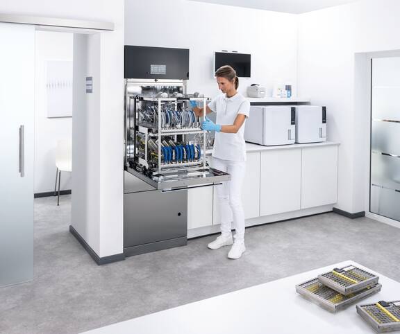 Een tandartsassistente bij een open SlimLine 7121 thermodesinfector in de tandheelkundige behandelingskamer