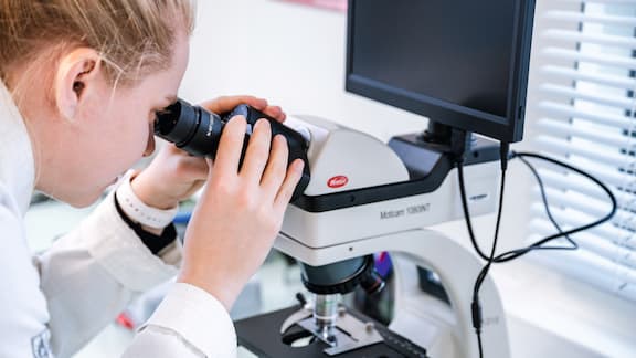 une femme qui observe dans un microscope
