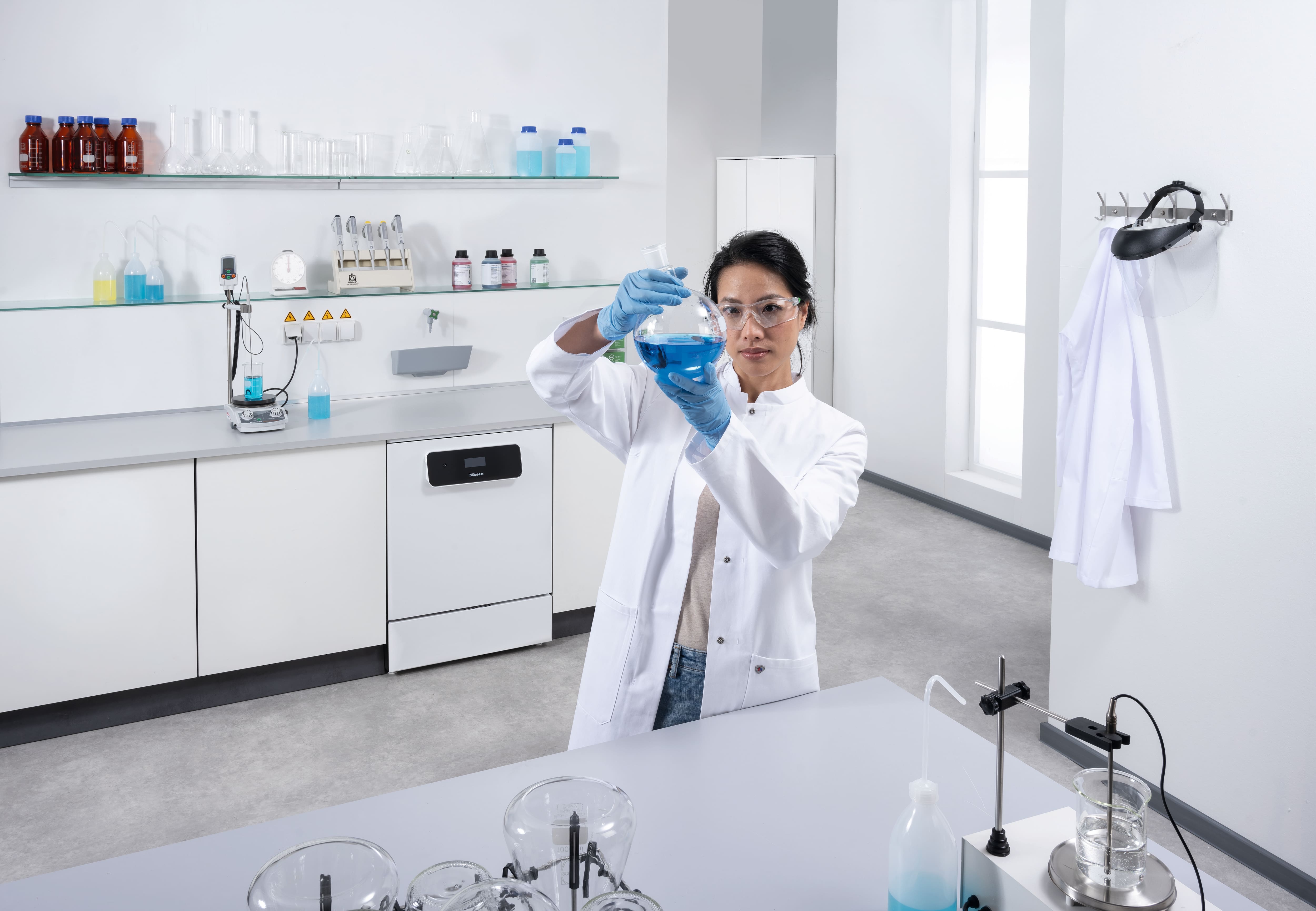 Technik laboratoryjny stojący przed ciągiem jednostek laboratoryjnych. w tle widoczna jest myjnia laboratoryjna ExploreLine PLW 8604 ze stali szlachetnej.