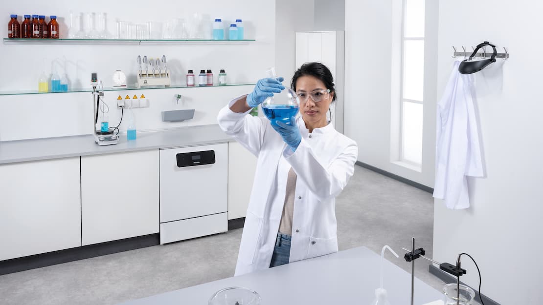 Technik laboratoryjny stojący przed ciągiem jednostek laboratoryjnych. w tle widoczna jest myjnia laboratoryjna ExploreLine PLW 8604 ze stali szlachetnej.