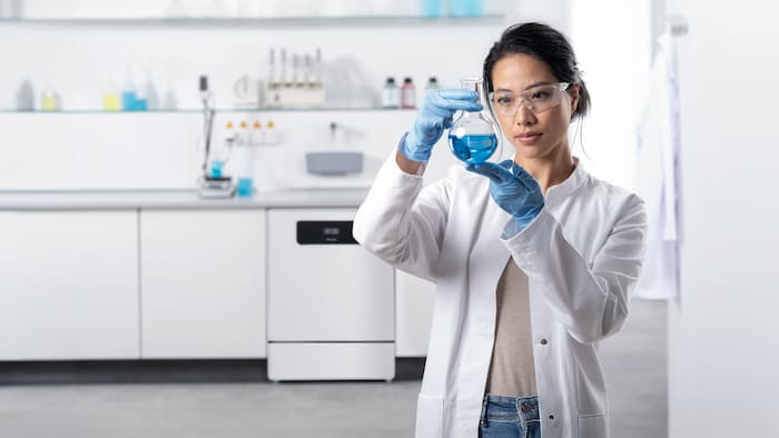 Technik laboratoryjny stojący przed ciągiem jednostek laboratoryjnych. w tle widoczna jest myjnia laboratoryjna ExploreLine PLW 8604 ze stali szlachetnej.