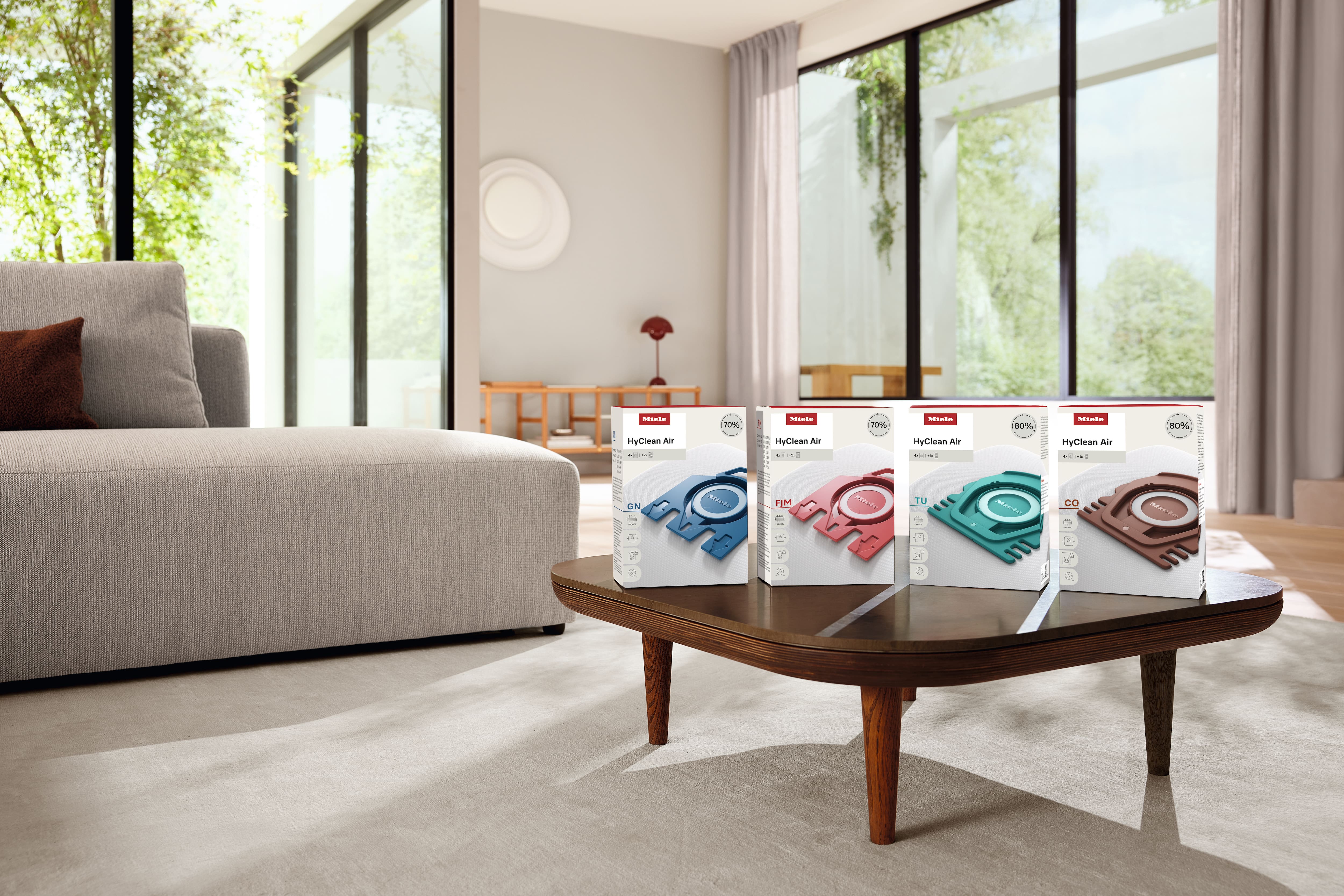 Four Miele vacuum bag boxes sitting on a wooden coffee table 