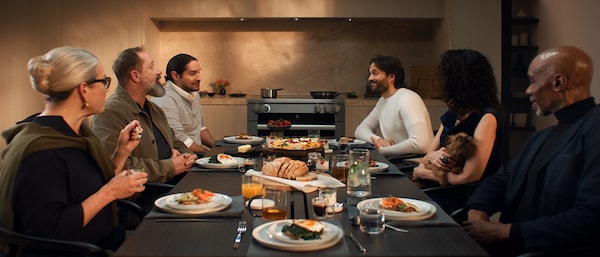 Group of friends having dinner around a table that sits in front of an induction range